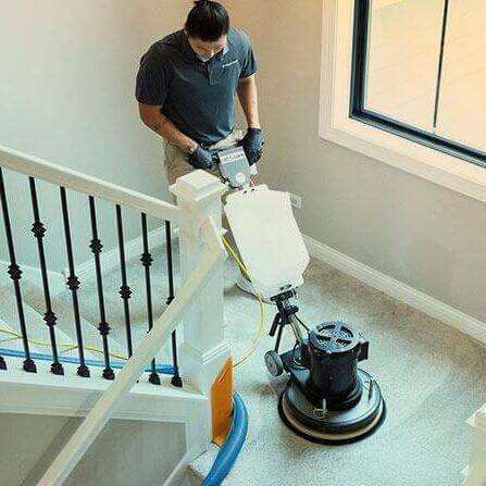 Green Clean team member cleaning carpet on stairs