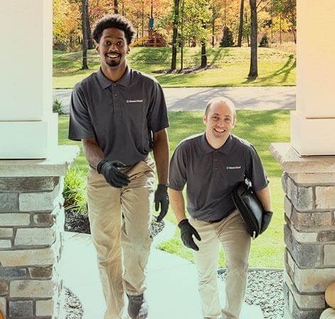 Two smiling Green Clean team members walking up to a door