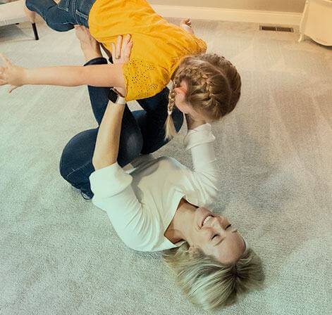 A mother playing with her child on clean carpet