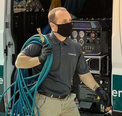 A Green Clean team member carrying a hose