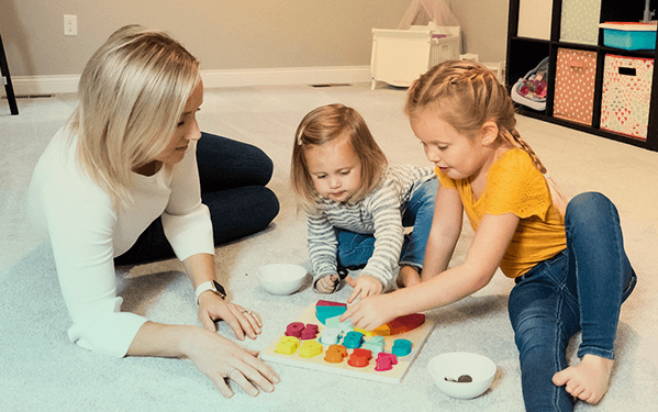 Mother and children playing together on clean carpet