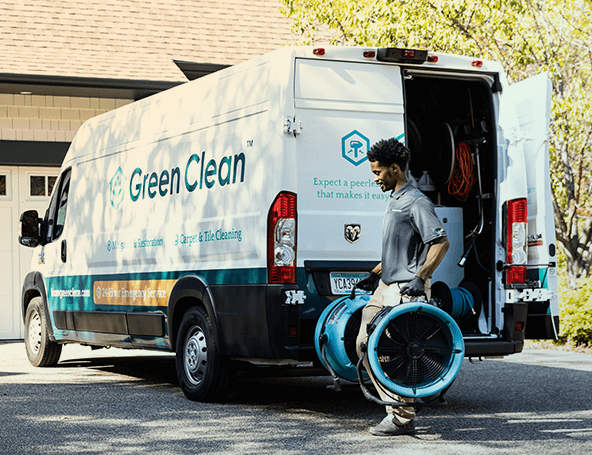 A Green Clean team member carrying equipment from their truck